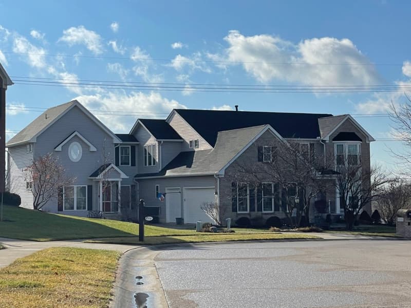 Large gray house with dark shingle roof on corner lot