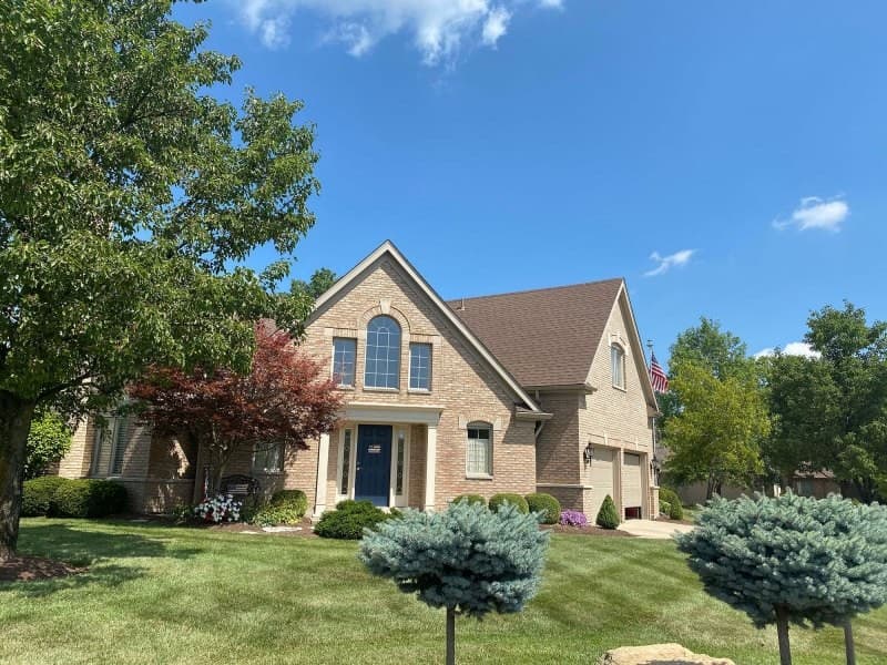 Brick house with steep shingle roof and arched window