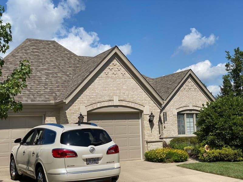 Brick house with shingle roof and white SUV