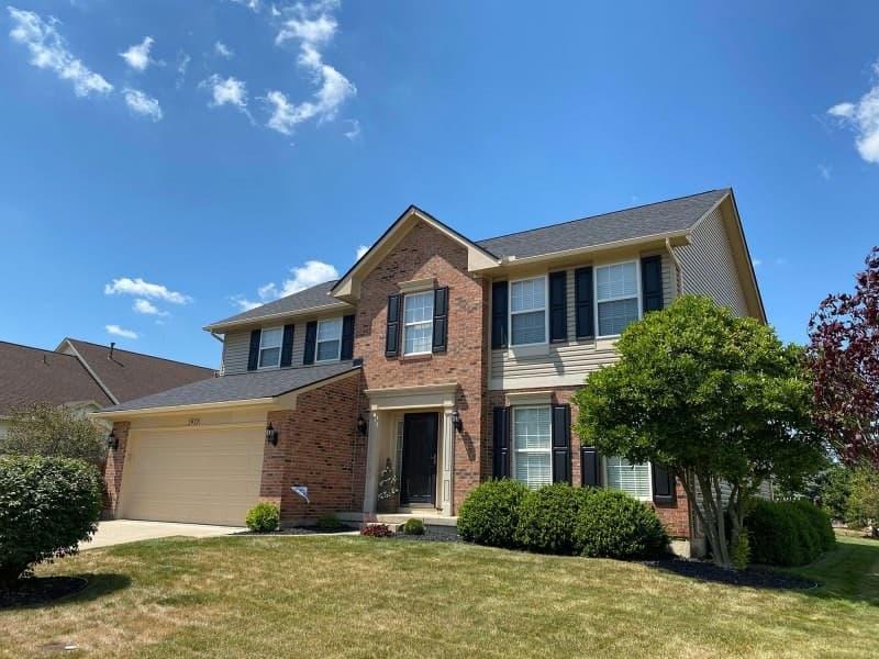 Two-story brick house with shingle roof and garage